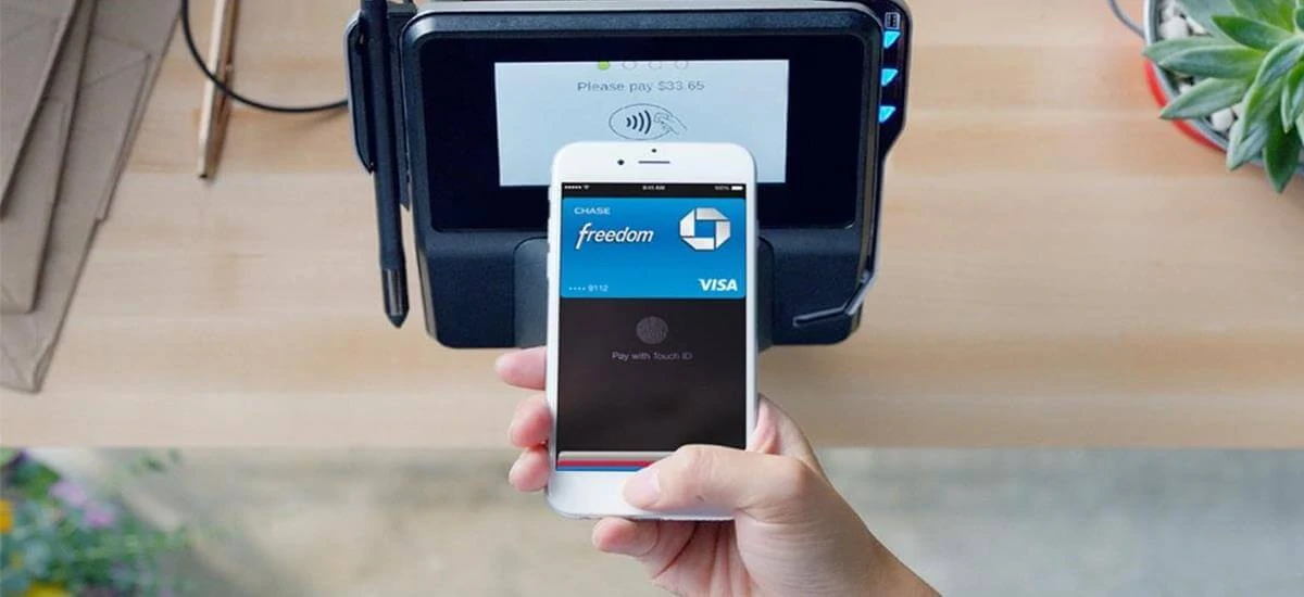 Mão com celular confirmando pagamento em máquina de cartão