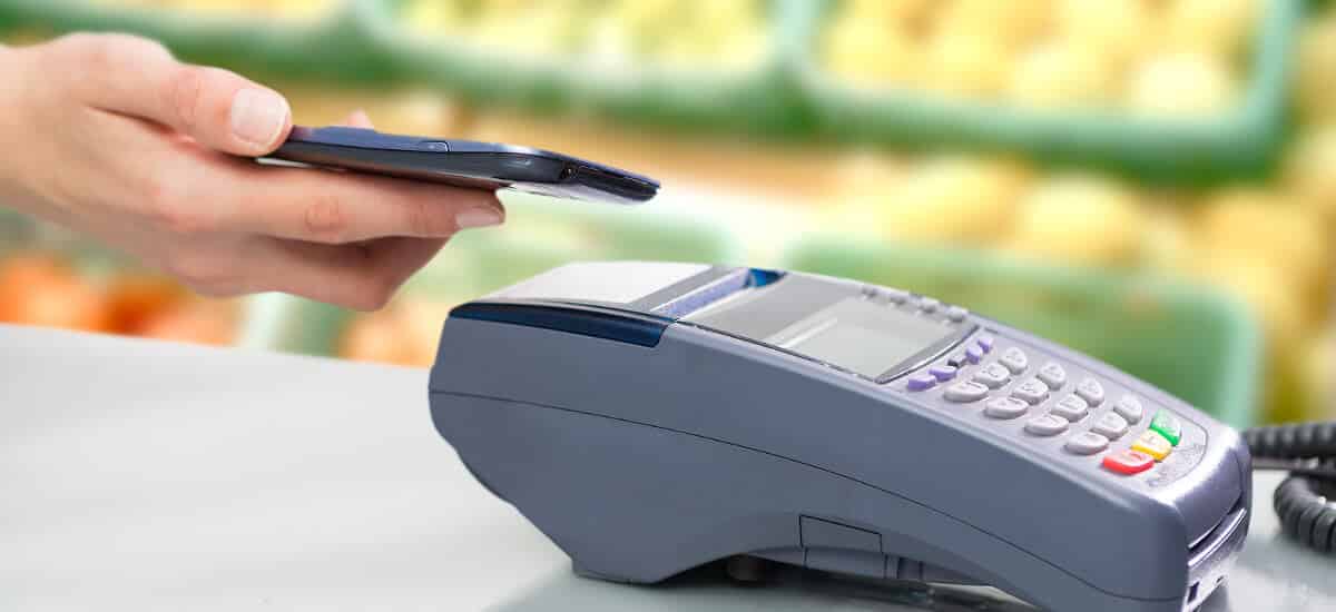 Mão posicionado cartão para pagamento NFC sobre máquina de cartão