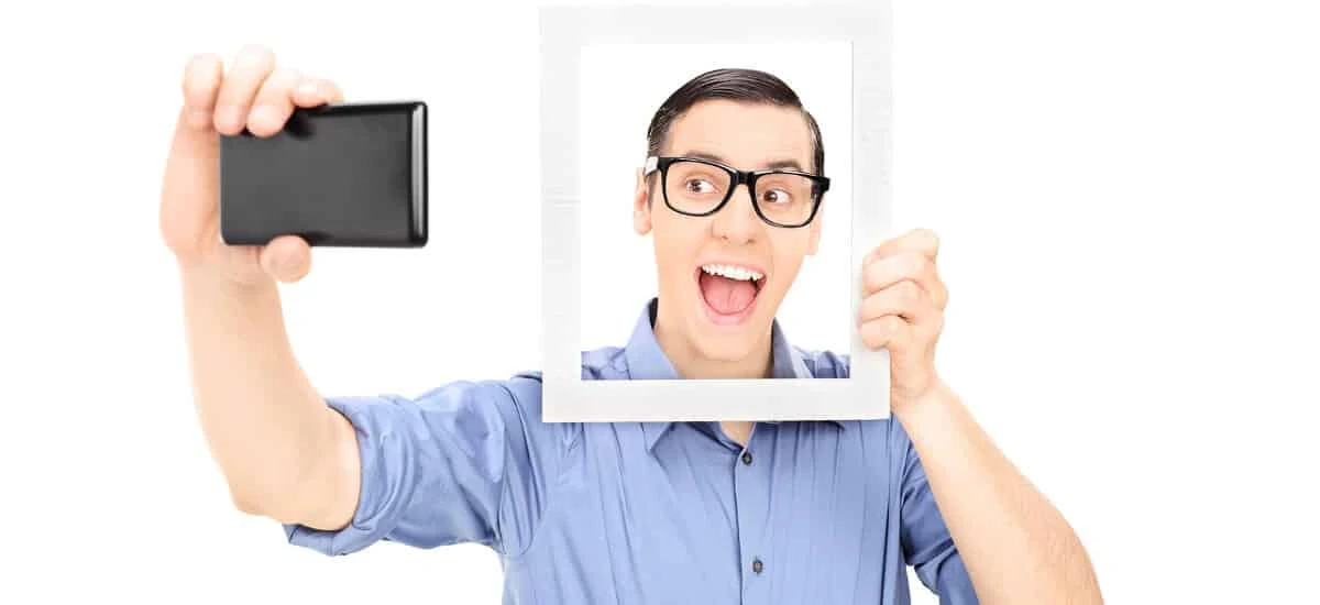 Homem de óculos tirando selfie com moldura de quadro em seu rosto