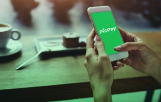 Mãos segurando celular com app PicPay sobre mesa de café