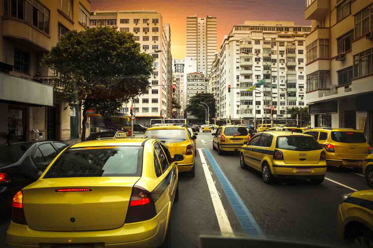 Fila de táxis engarrafados em rua de mão dupla de cidade grande