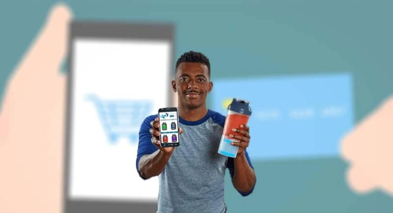 Homem segurando celular que mostra a Loja Virtual Uol e copo de suplemento na outra mão