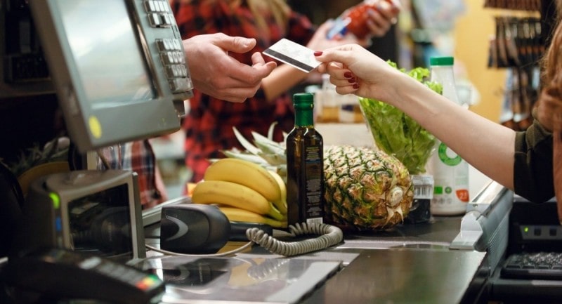 Foto ilustrando mulher fornecendo cartão em supermercado e o sistema PDV do mesmo