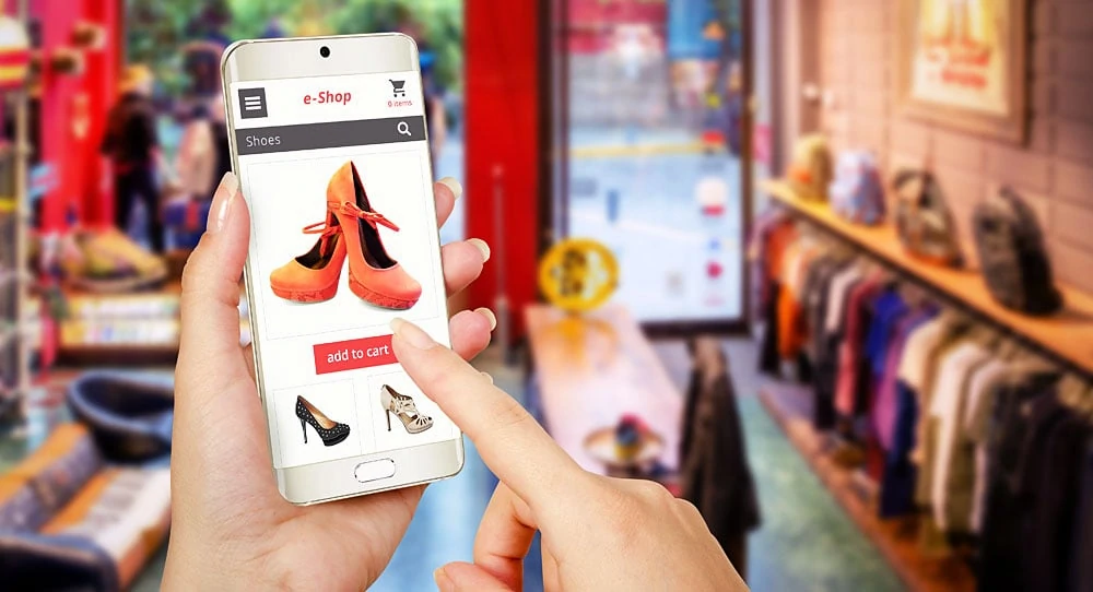 Ilustração de uma pessoa realizando compra em loja virtual pelo celular, com fundo de uma loja física