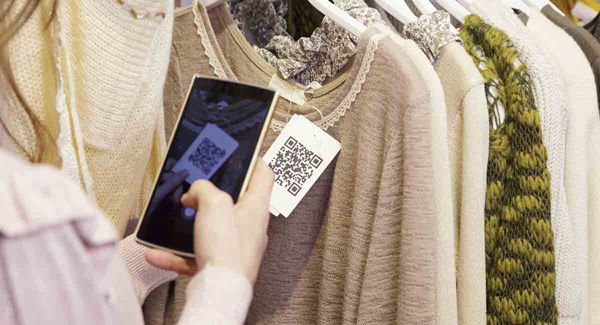 Mulher escaneando um QR Code com seu celular de uma etiqueta em uma blusa