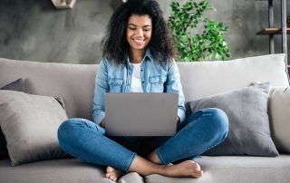 Mulher sentada no sofá criando loja virtual no laptop