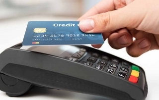 Mão aproximando cartão de máquina para pagar via NFC