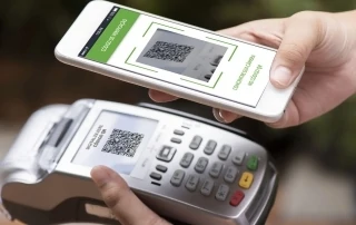 Máquina de cartão e celular realizando pagamento com QR Code